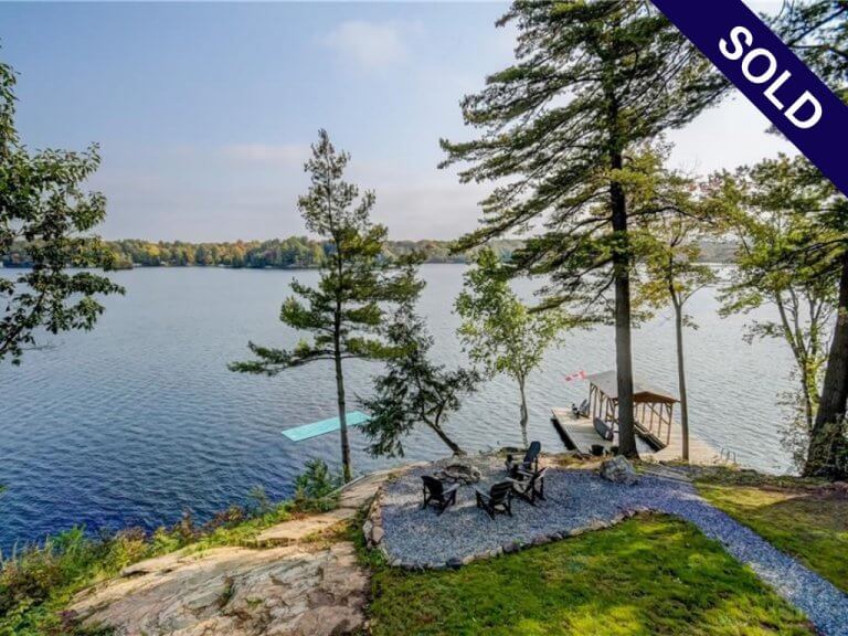 Sold sign in front of a Muskoka waterfront property, showcasing a successful real estate sale.